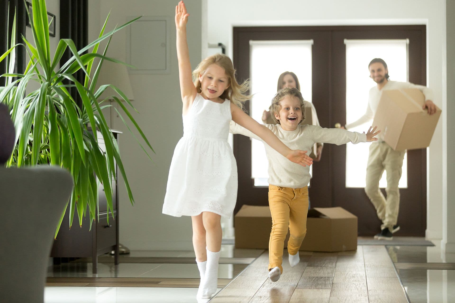 Happy family moving into a new home as excited children run through the front entryway, representing the comfort, peace of mind, and confidence that comes with a safe and reliable home environment.