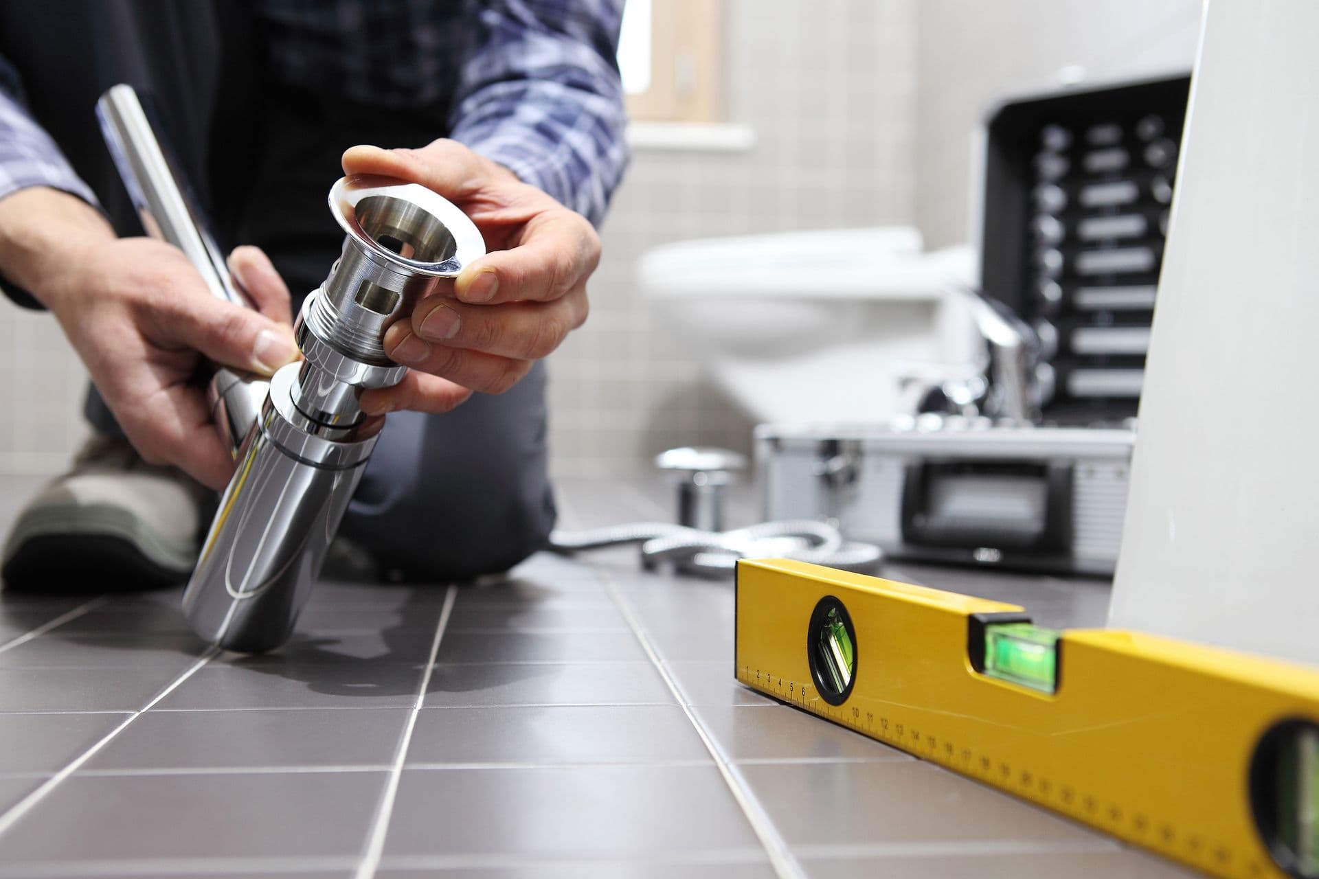 Plumber installing or replacing a bathroom faucet using professional tools and a level during a residential bathroom plumbing installation.