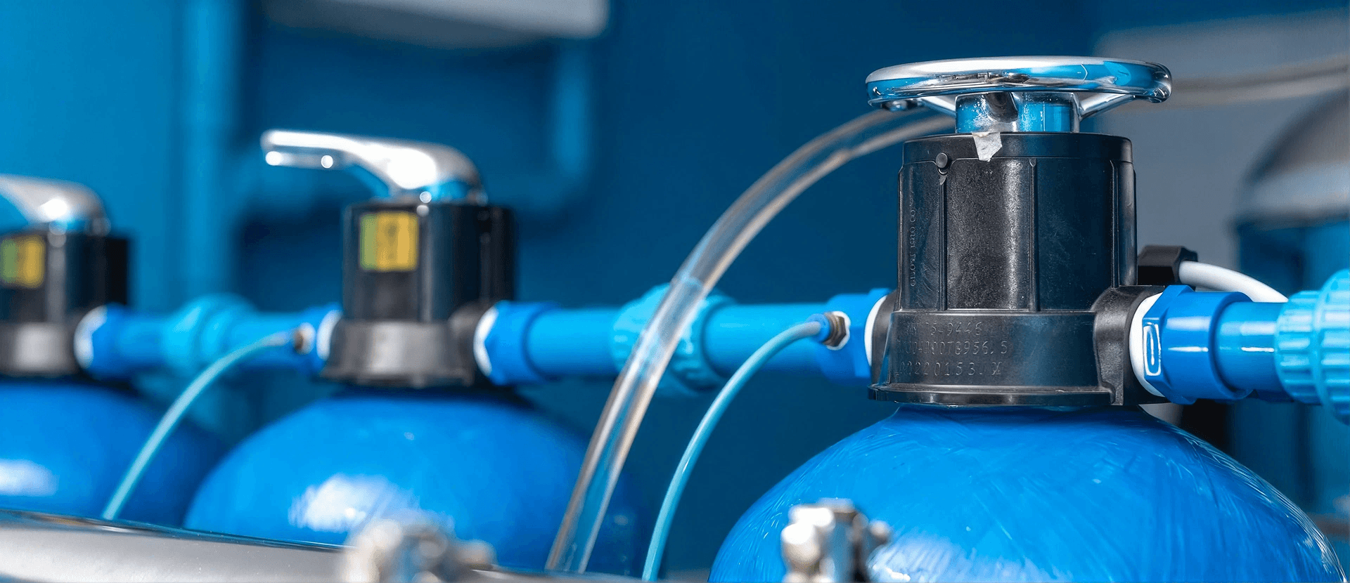 Close-up of a whole-home water softener system with resin tanks, control valves, and plumbing connections designed to reduce hard water throughout a residential property.