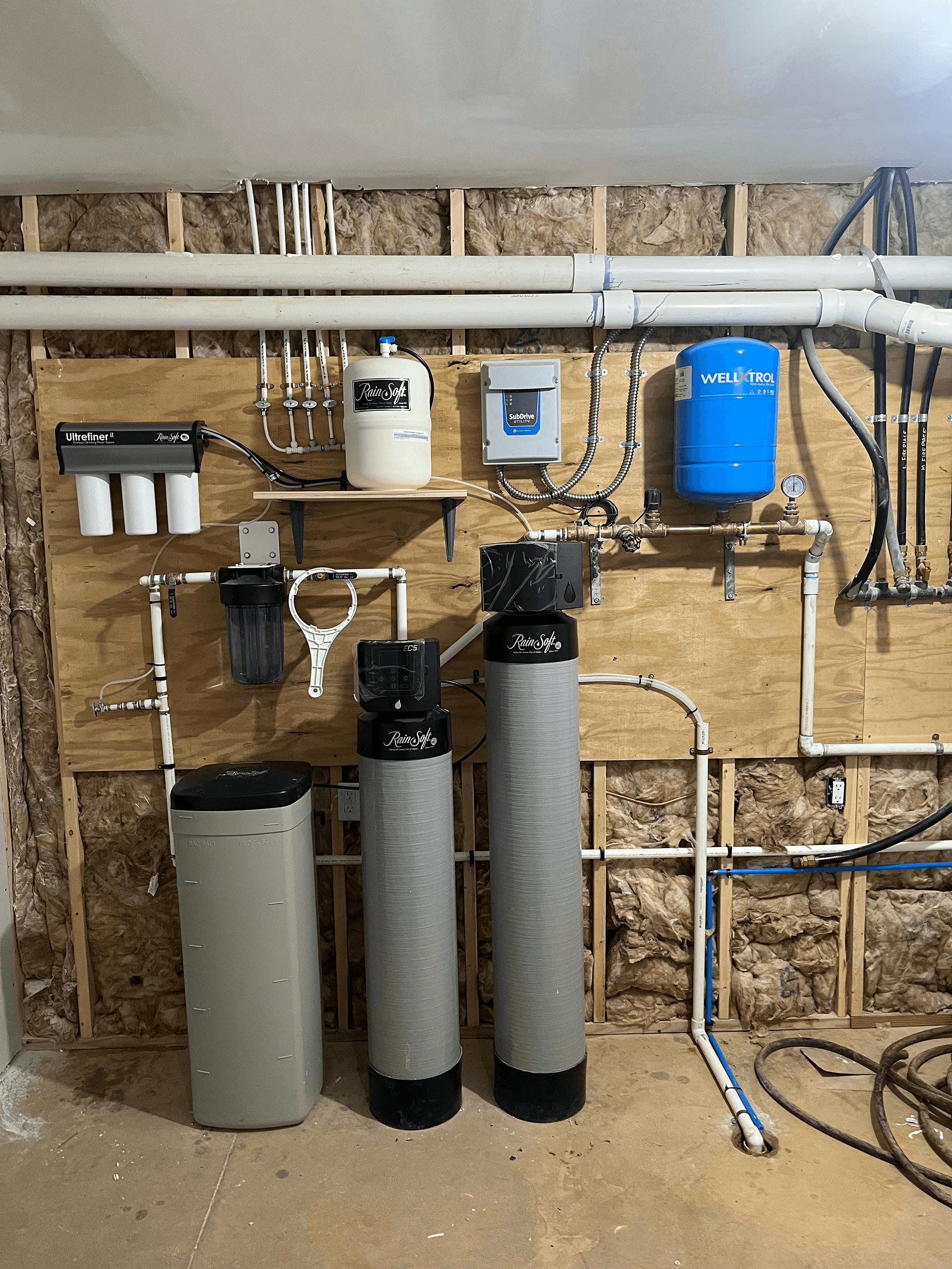 Professionally installed RainSoft whole-home water treatment system featuring dual filtration tanks, water softener, sediment filter, reverse osmosis components, and well pressure tank.