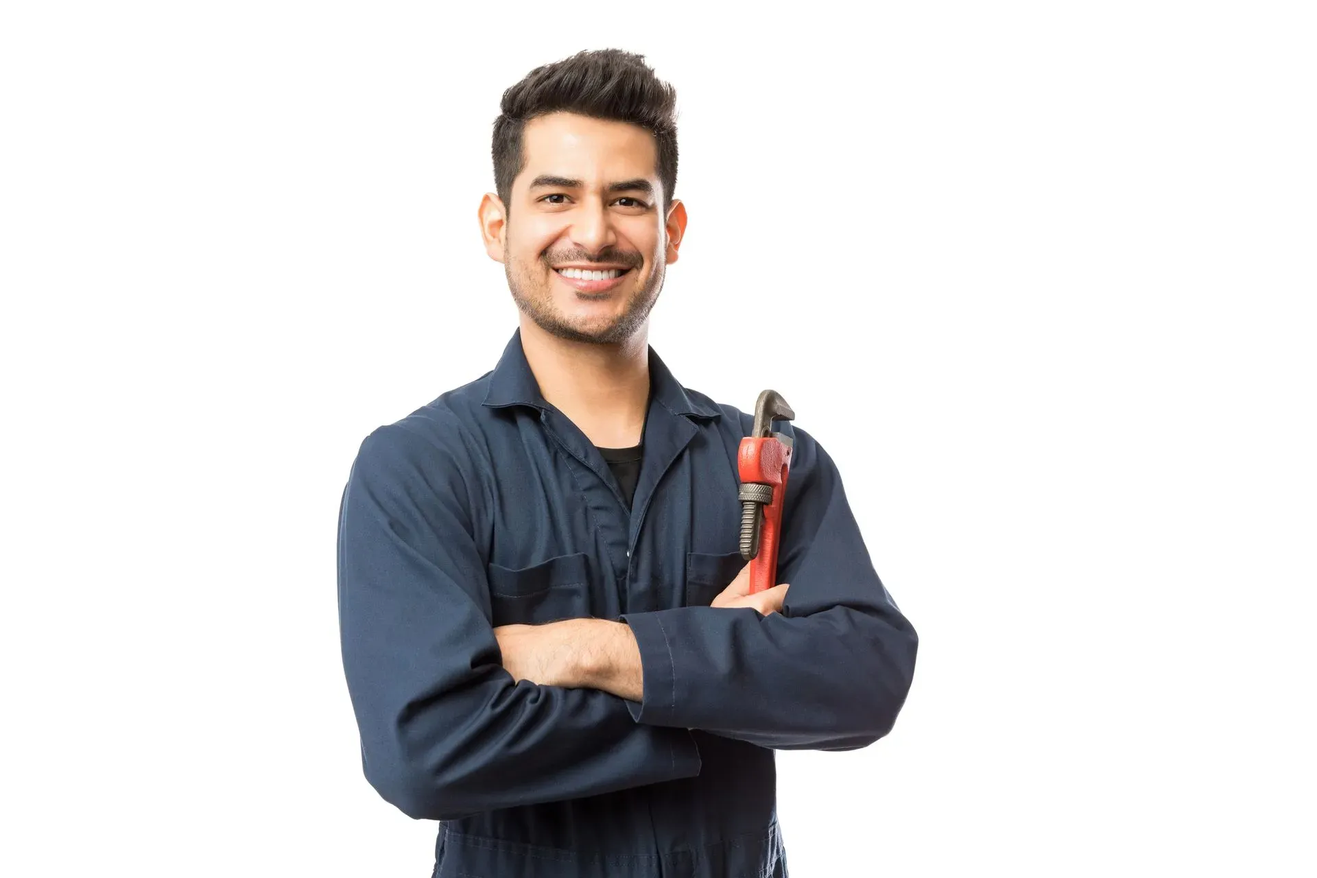 Smiling man in blue coveralls holding a red pipe wrench. He stands confidently with arms crossed against a plain white background, conveying reliability.